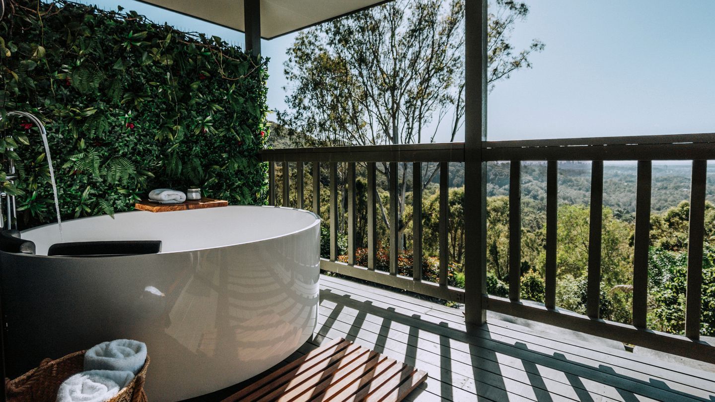 A spa area with a hot tub, a wooden deck, and a view of the surrounding forest.