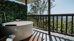 Ett spaområde med ett bubbelbad, en träveranda och utsikt över den omgivande skogen.