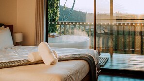 Ein Hotelzimmer mit Bett, großem Fenster mit Gartenblick und Whirlpool.