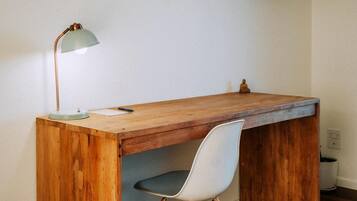 A wooden desk with a chair, a lamp, and a television mounted on the wall.