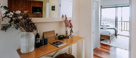 Un dormitorio con cama, un escritorio de madera con espejo, un letrero de bienvenida y vistas a un balcón.