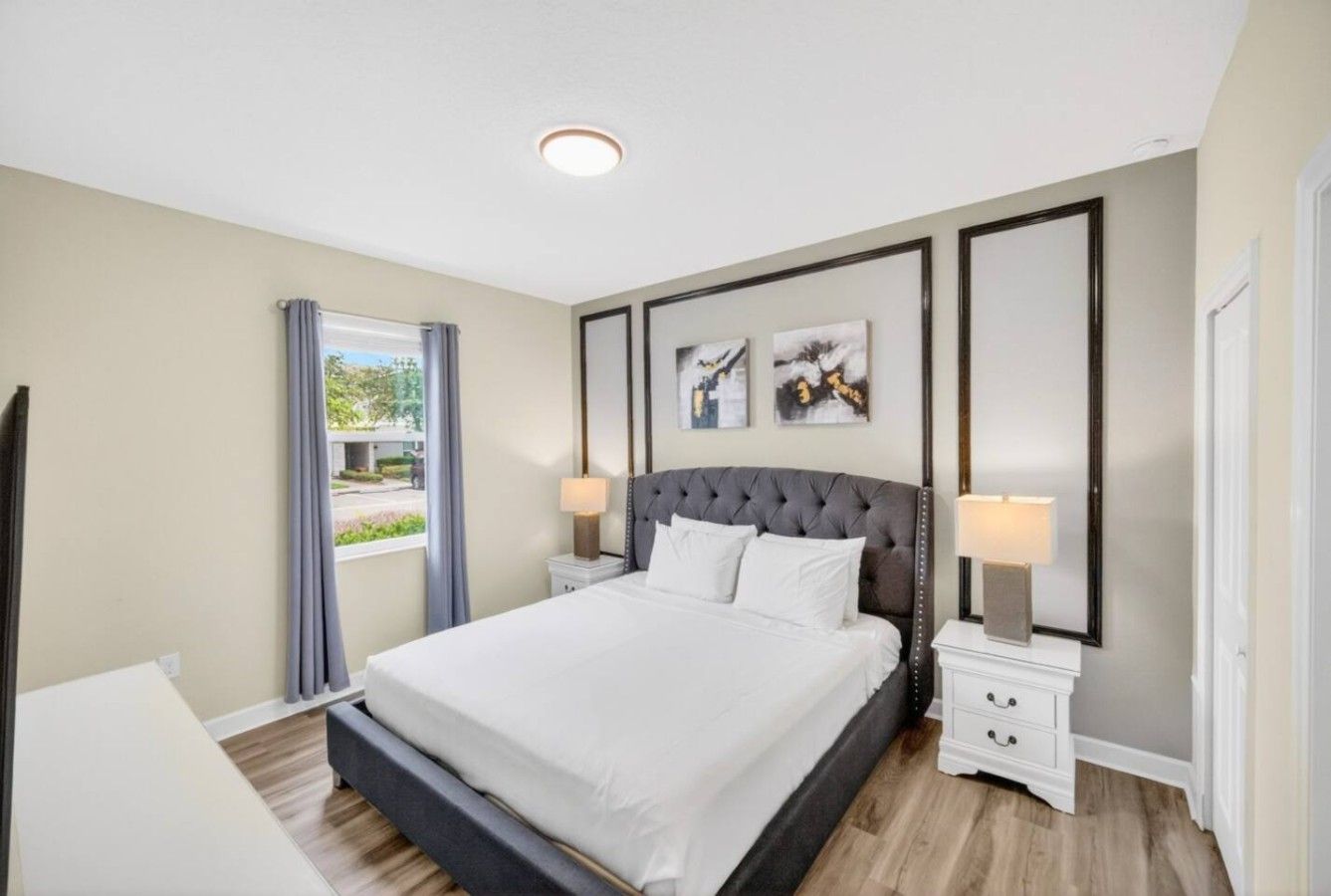 A modern bedroom with a large bed, bedside tables, and a window with curtains.