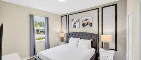 Une chambre moderne avec un grand lit, des tables de chevet et une fenêtre avec des rideaux.