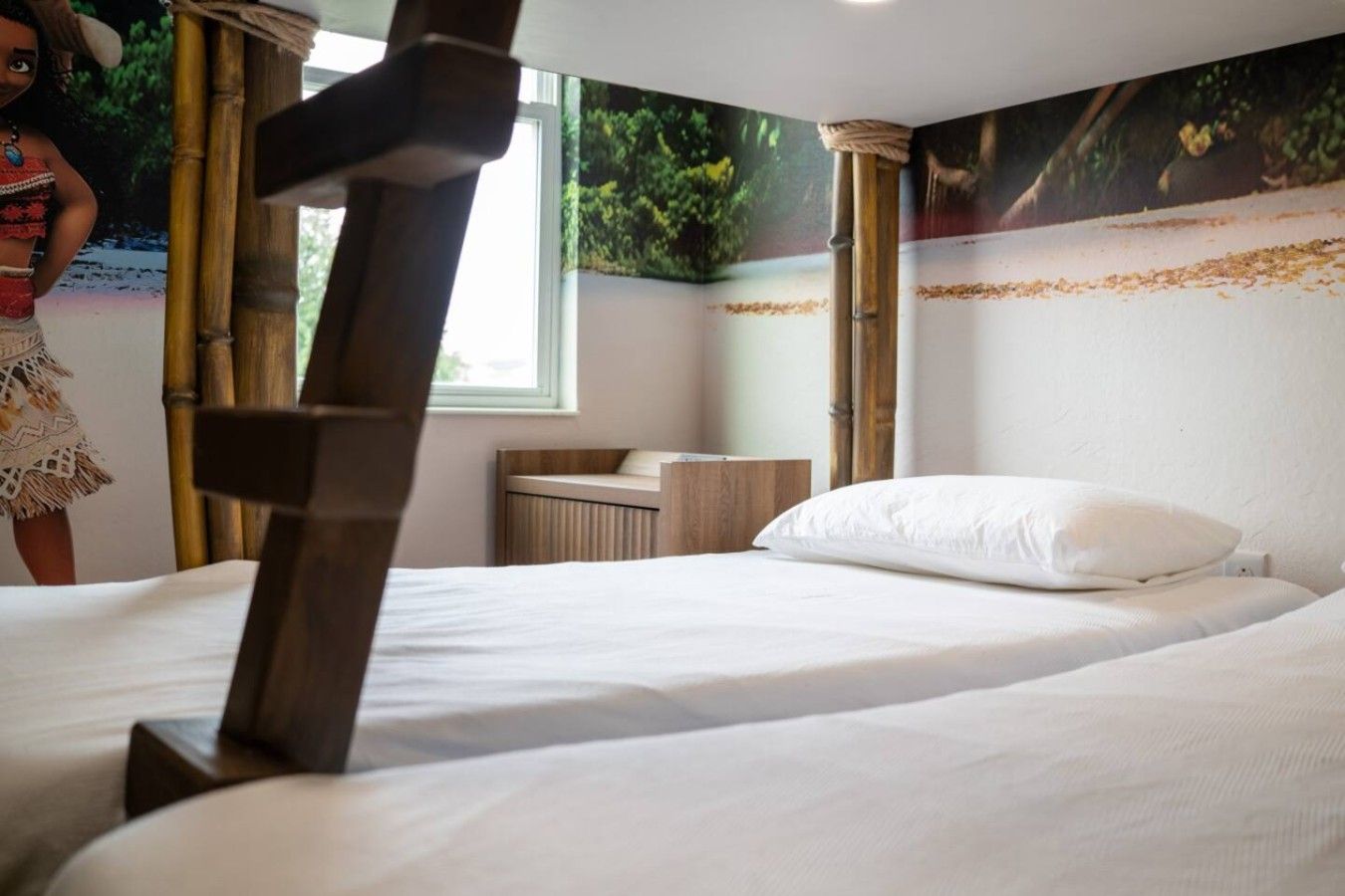 A hotel room with a bed, a wooden headboard, a window, and a wall with a nature-themed mural.