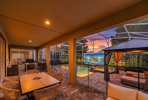 An outdoor patio with a pool, dining area, and seating. - Ultimate 9BR Villa | Pool | Resort | Near Disney (Kissimmee)