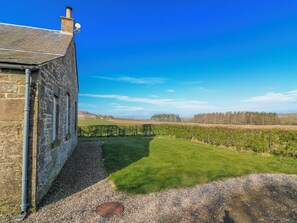 A stone building with a clear view of a vineyard and distant hills. - Meadowgreen Farmhouse (Forfar)
