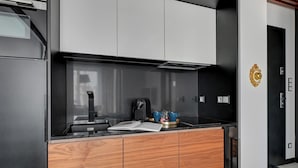 Une cuisine moderne avec un plan de travail noir, des meubles en bois et une machine à café.
