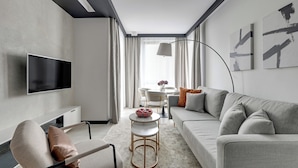 Un salon moderne avec un canapé, un fauteuil, un téléviseur et des œuvres d’art accrochées au mur.