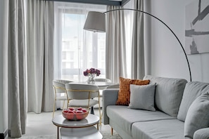 A modern living room with a grey sofa, a round coffee table, and a white dining table with chairs. - Helsinki Luxury Apartment Sopot (Sopot)