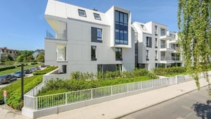 Un immeuble résidentiel moderne à plusieurs étages, doté de balcons, d’une entrée sécurisée et offrant une vue dégagée sur les environs.