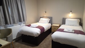 Una habitación de hotel con dos camas, un escritorio y una silla.
