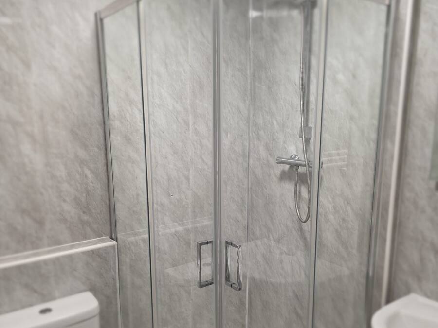 A modern bathroom with a glass-enclosed shower, a toilet, and a sink.