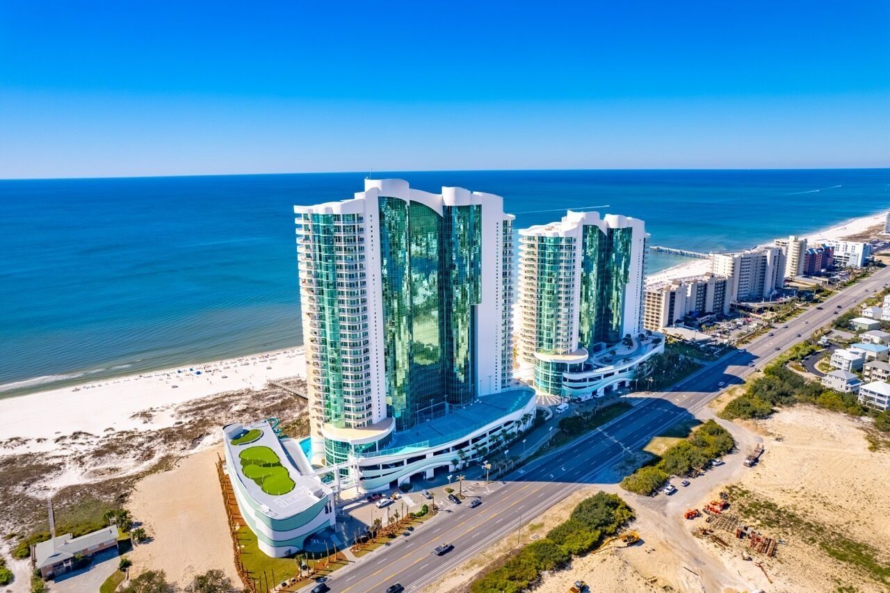 Een hoog hotel met modern design, nabij een strand en een helder uitzicht op de oceaan.