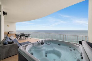 Ein Balkon mit Whirlpool, Sitzgelegenheit und Meerblick.