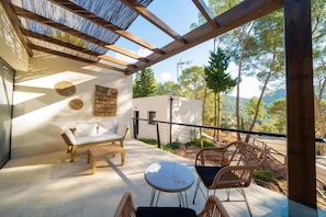 A covered outdoor seating area with a table and chairs, a sofa, and a pergola structure.