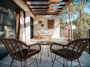 A covered patio with wicker chairs and a table, a pergola, and a view of trees and mountains.