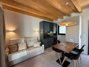 A modern living space with a sofa, dining table, and kitchen area.