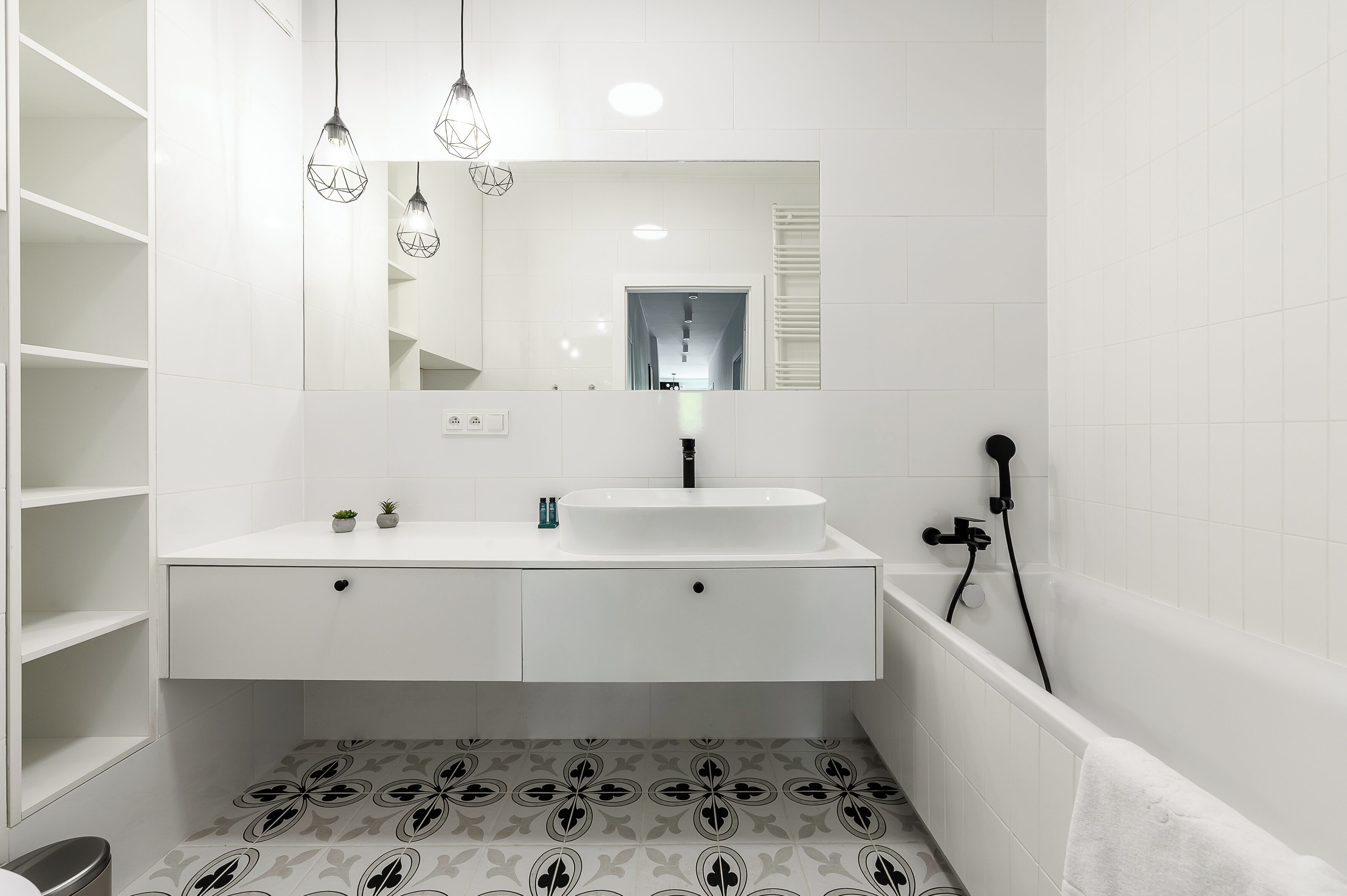 A modern bathroom with a white vanity, a large mirror, and a bathtub.