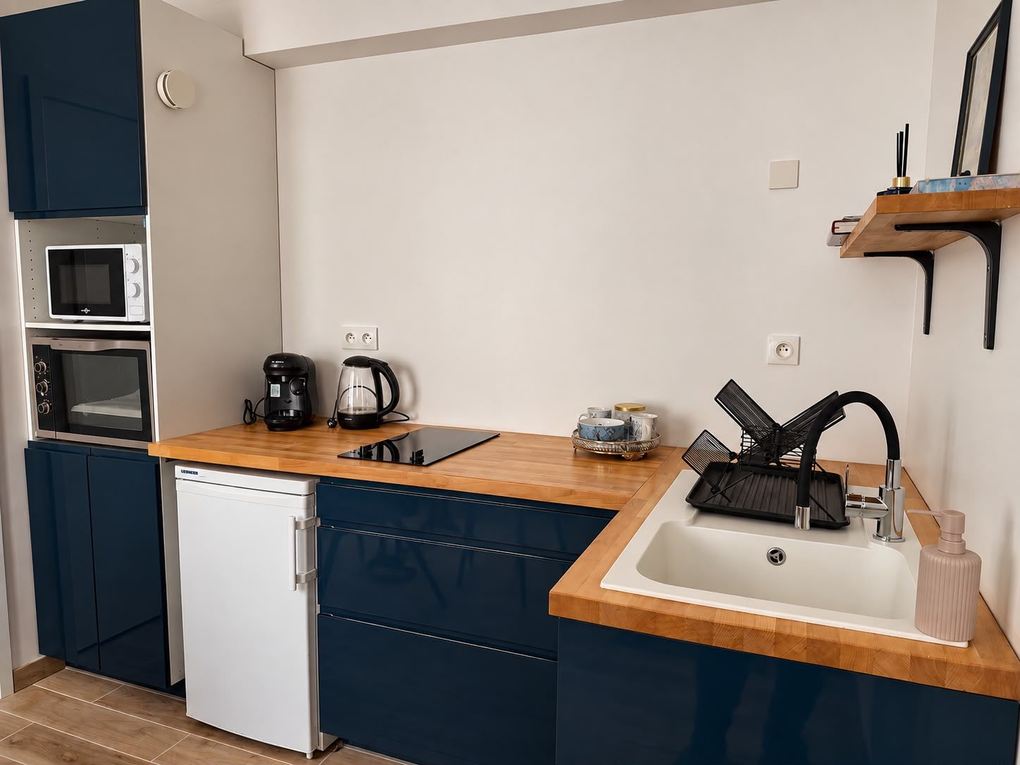 Una cocina compacta equipada con lavavajillas, cafetera y lavabo.