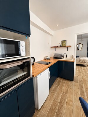 A compact kitchen with a microwave, oven, and refrigerator, a wooden countertop, and a sink. - L'Opaline - On the banks of the Seine near Giverny (Vernon)