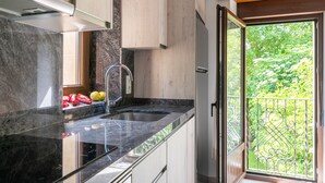 Cocina con encimera de granito, pileta de acero inoxidable y vista a la vegetación a través de una puerta corredera.