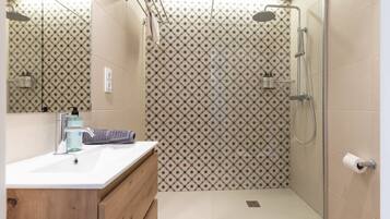 A modern bathroom with a shower, toilet, and sink.