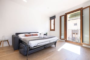 A modern bedroom with a bed, a small table, and a view of the outside. - Merceria Suites - Unik Vacation (Tarragona)