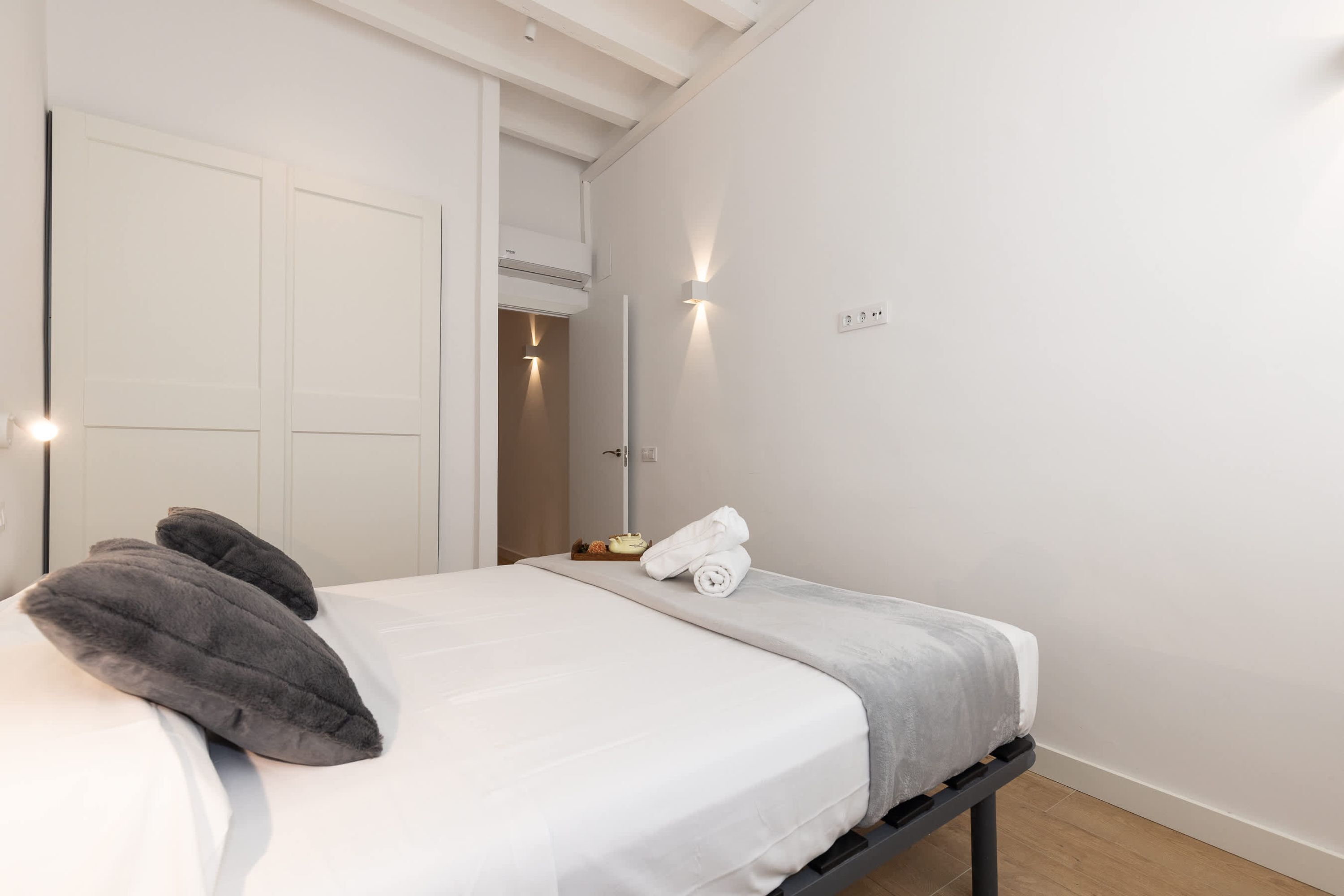 A hotel room with a bed, pillows, a towel, and a nightstand.