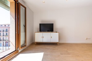 Quarto com uma grande porta de vidro deslizante, um armário branco com TV de tela plana e piso revestido de azulejos.