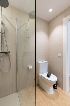 Uma casa de banho moderna com duche, sanita e divisória de vidro.