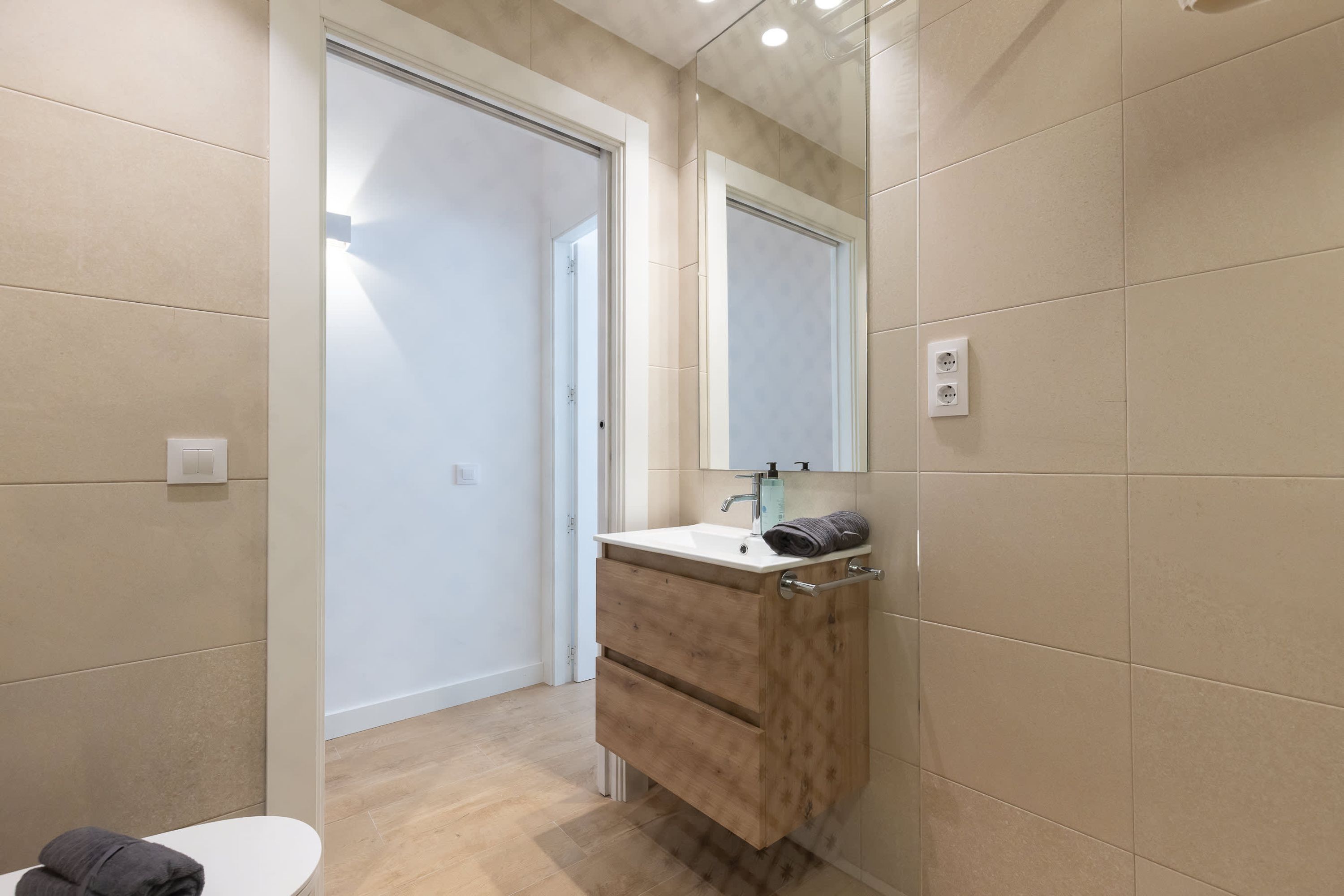 Un baño con inodoro, lavamanos con espejo y un armario de madera.