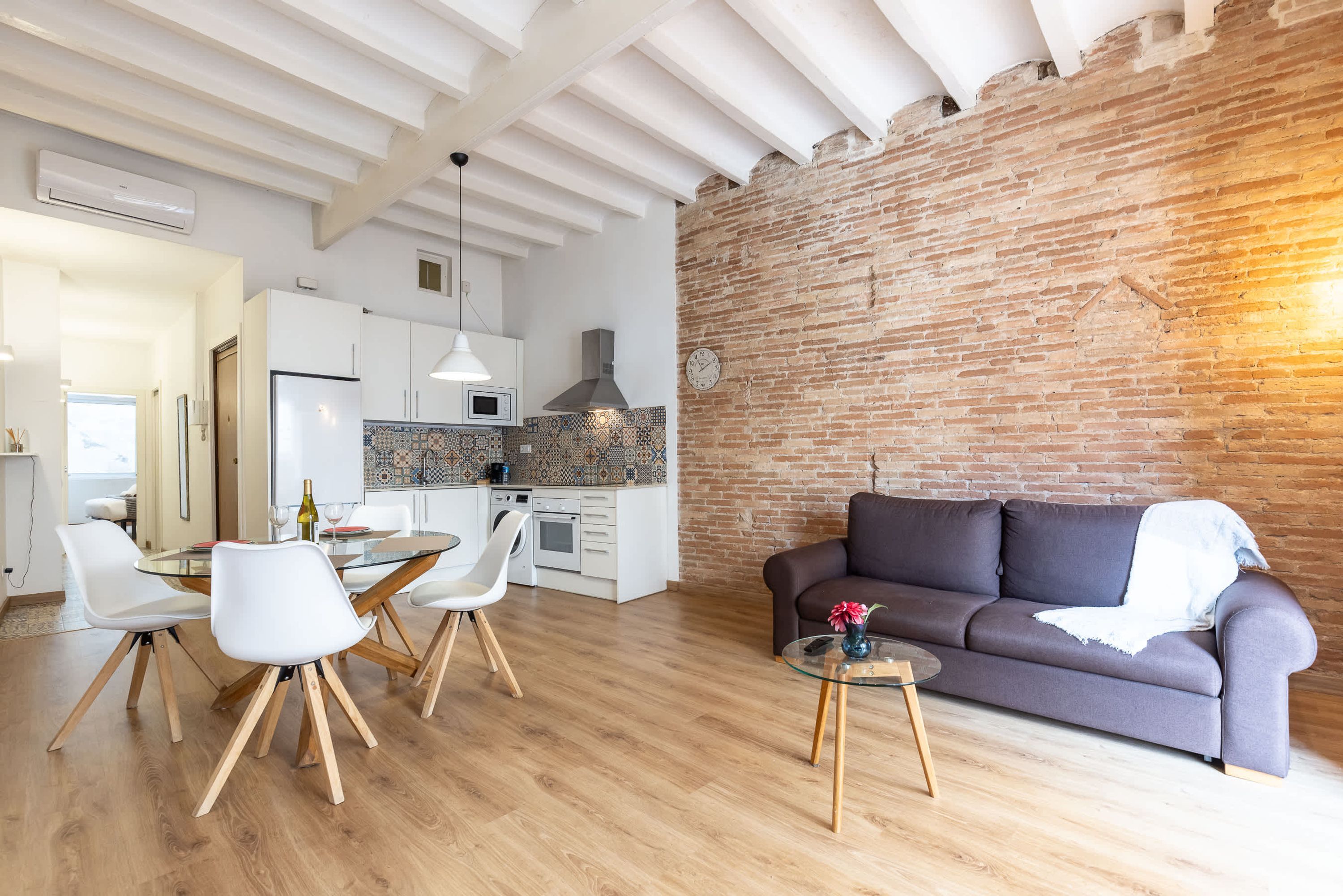 A modern living space with a kitchen, dining area, and a brick wall.