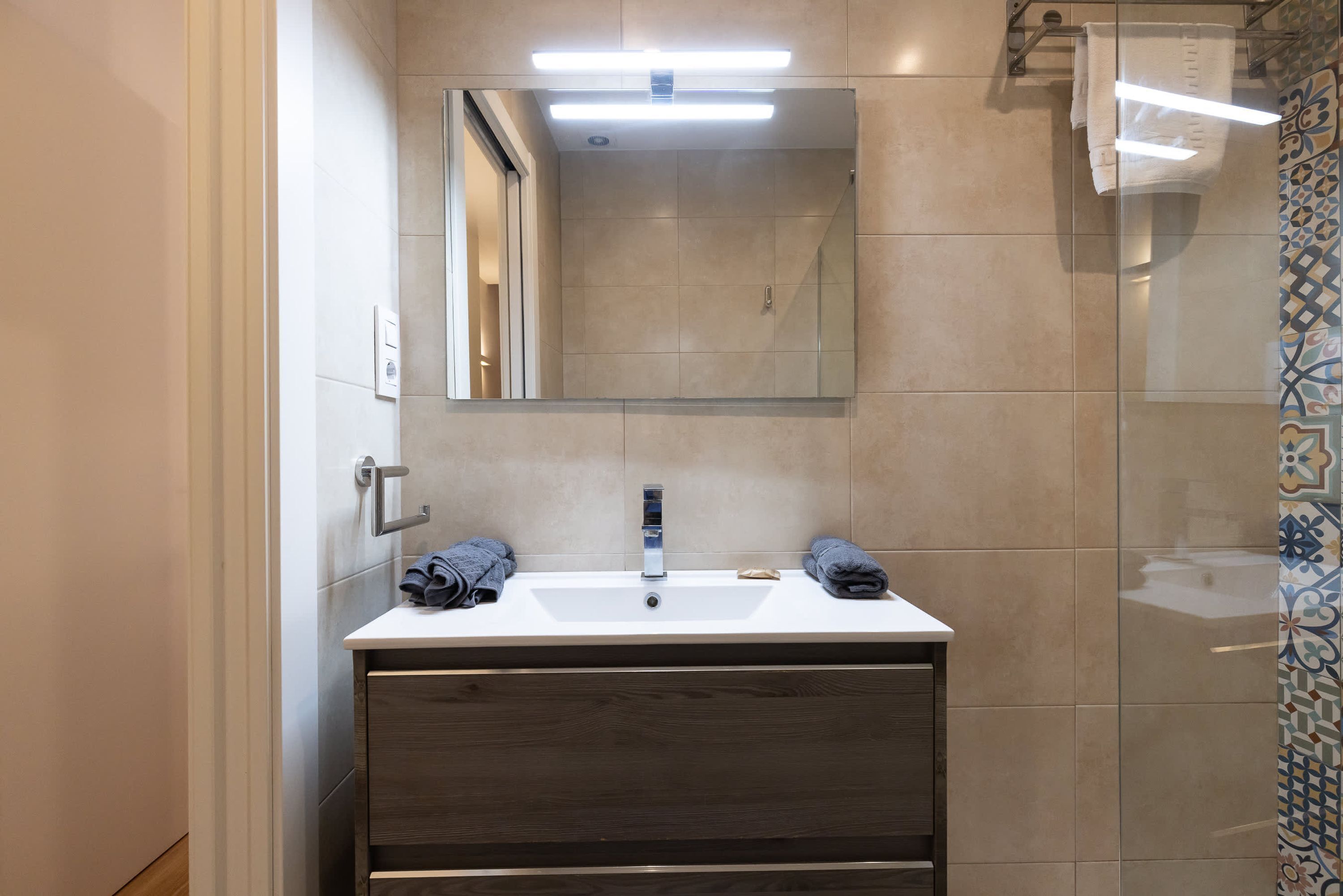 A modern bathroom with a large mirror, two sinks, and a shower area.