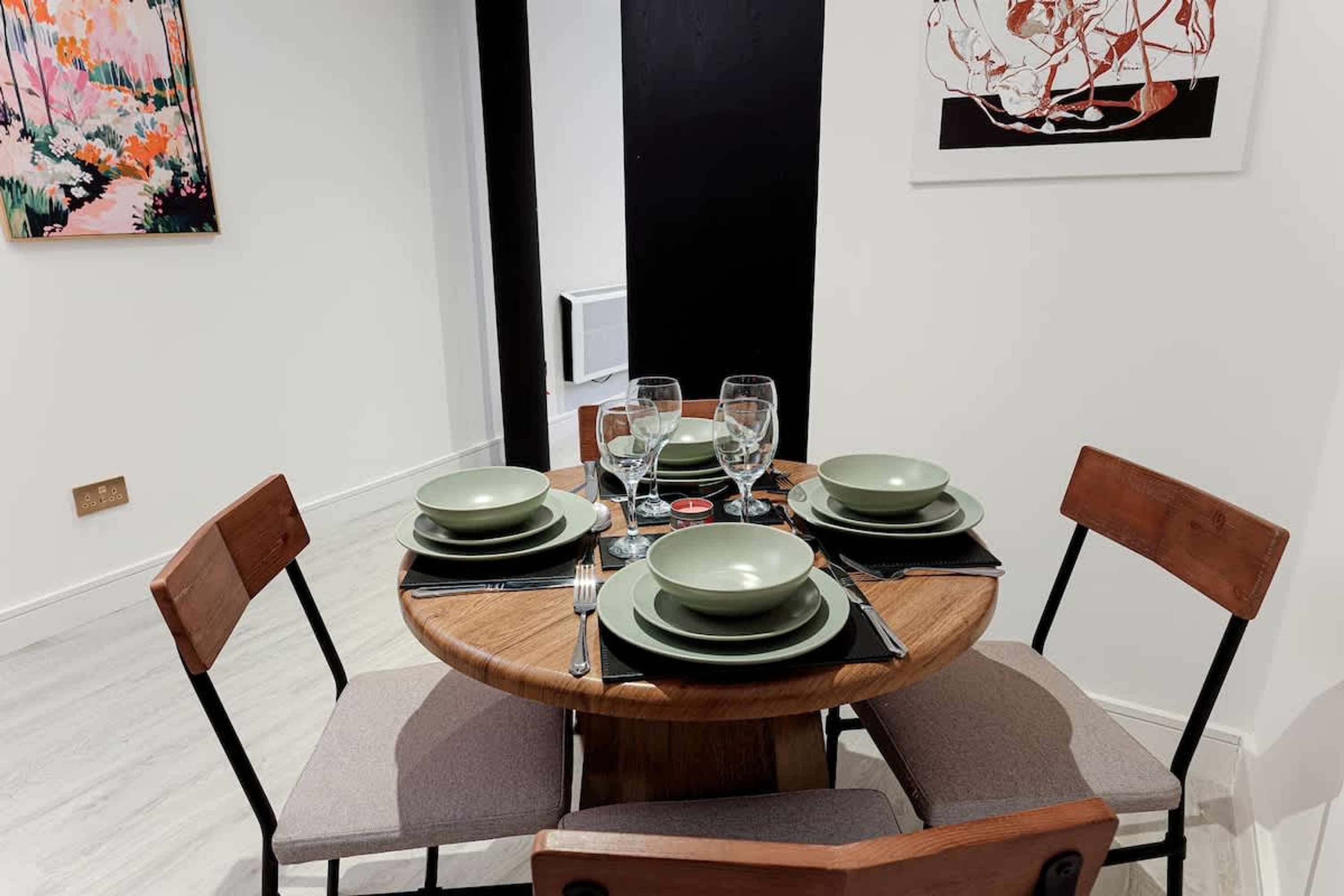 Une table à manger dressée avec des assiettes, des verres et des couverts, entourée de chaises.