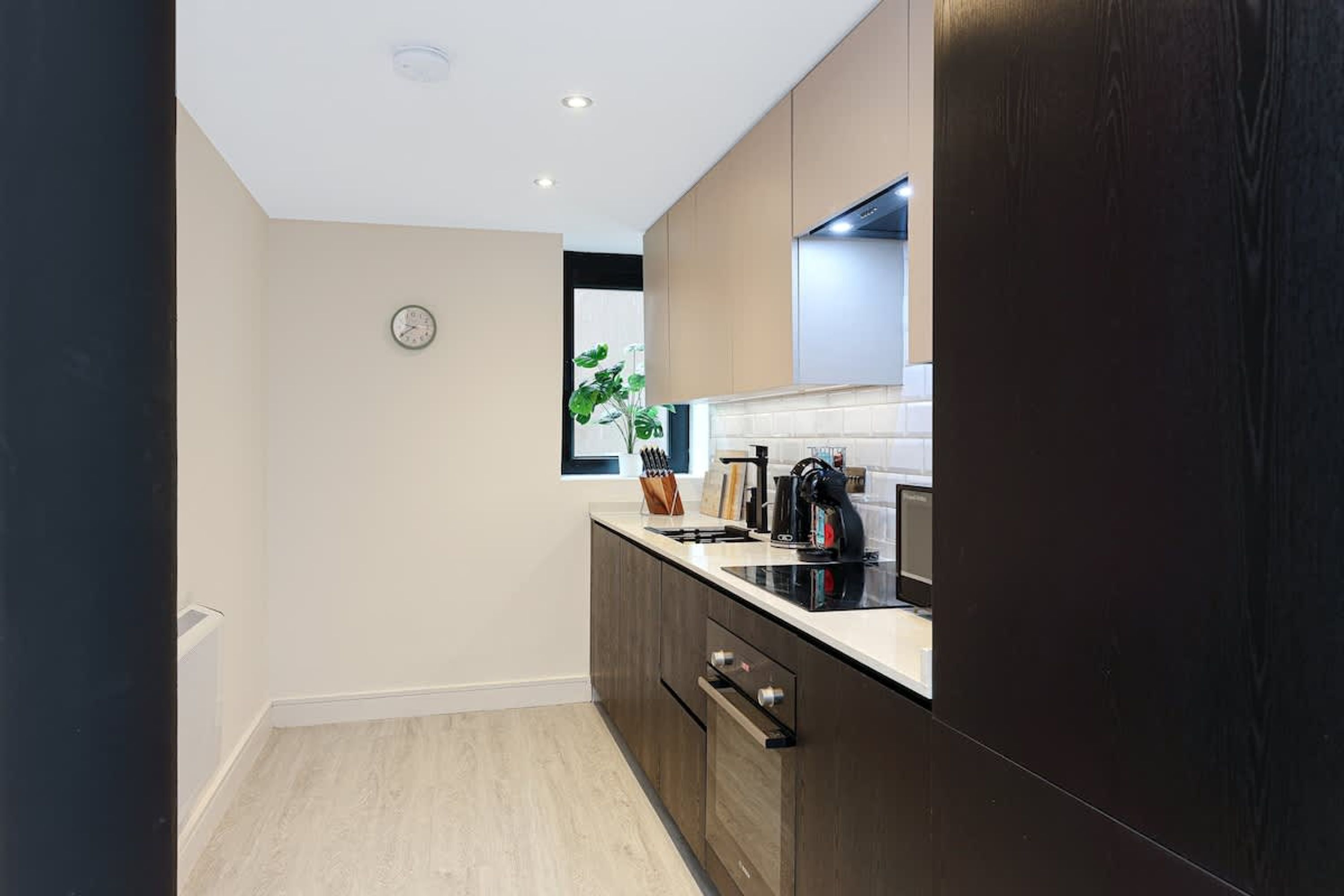 A modern kitchen with wooden cabinets, a black countertop, and a window with a view.