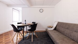 A room with a dining table, chairs, a sofa, a clock, and a patterned rug. - Central Part Alta 2 - Unik Vacation (Tarragona)