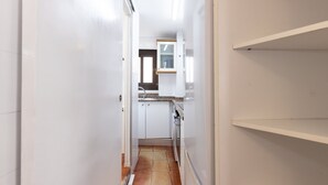 A narrow hallway leading to a kitchen with white cabinets, a countertop, and a window above the sink. - Central Part Alta 2 - Unik Vacation (Tarragona)