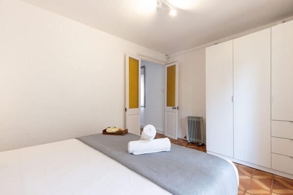 Ein Hotelzimmer mit Bett, einem kleinen Tisch mit Tablett, Heizkörper und Kleiderschrank.