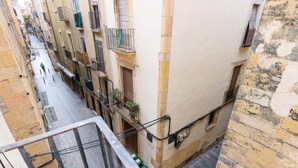 A narrow street with buildings on either side, balconies with railings, and a pedestrian walkway. - Central Part Alta 2 - Unik Vacation (Tarragona)
