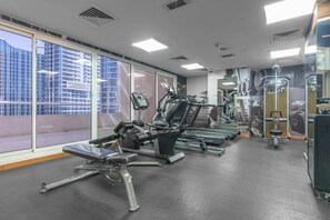 Ein Fitnessstudio mit unterschiedlichen Trainingsgeräten, großen Fenstern und Blick auf Gebäude.