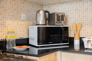 Eine Küche mit Mikrowelle, Toaster und Wasserkocher auf der Arbeitsplatte, einem Teller mit Essen und zwei Wasserflaschen.