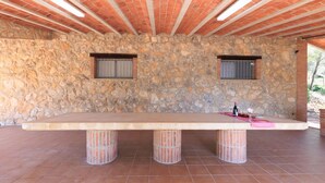 A stone wall with a large table and two windows. - Masia Garriga in Tarragona (Alcover)