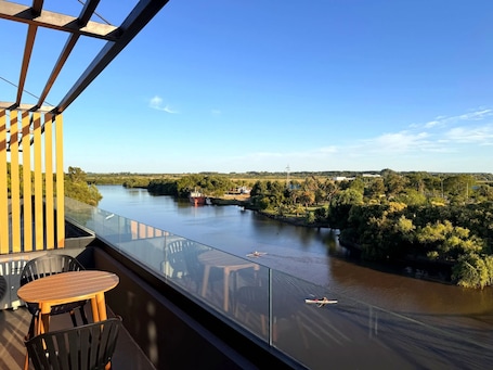 Ein Balkon mit Glasgeländer, der auf einen Fluss blickt, mit Tisch und Stühlen.. Carmelo Postal in Carmelo