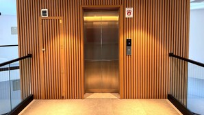 An elevator with vertical wooden paneling, a digital display, and a safety sign. - Carmelo Postal in Carmelo (Carmelo)