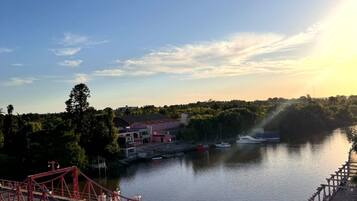 A river with a red bridge, boats, and a building with a red roof.