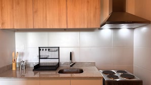 A kitchen with wooden cabinets, a stainless steel stove, a black wire rack, and a sink. - Carmelo Postal in Carmelo (Carmelo)