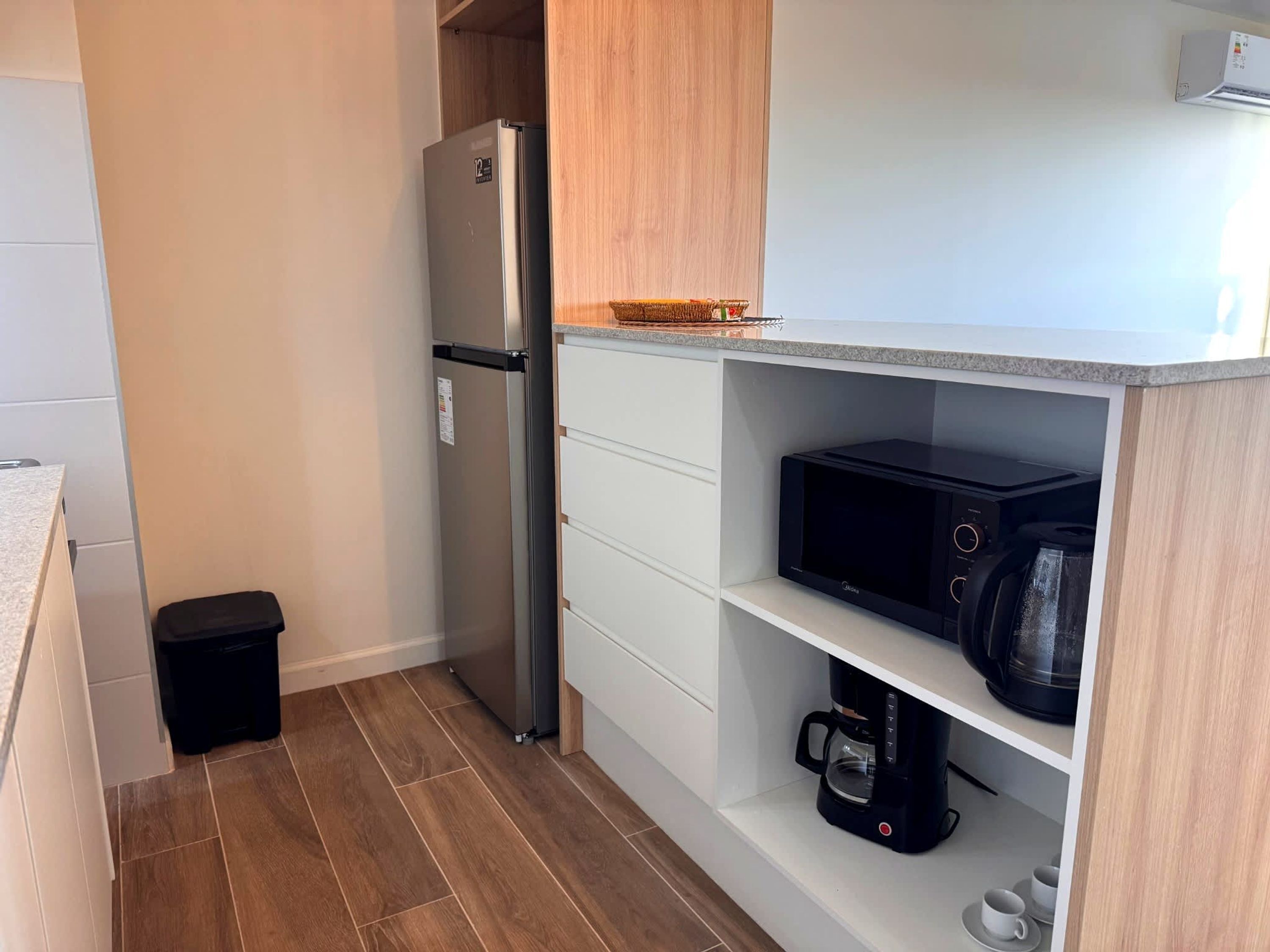 Una cocina compacta equipada con refrigerador, microondas y cafetera.