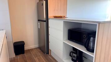 Una cocina compacta equipada con refrigerador, microondas y cafetera.