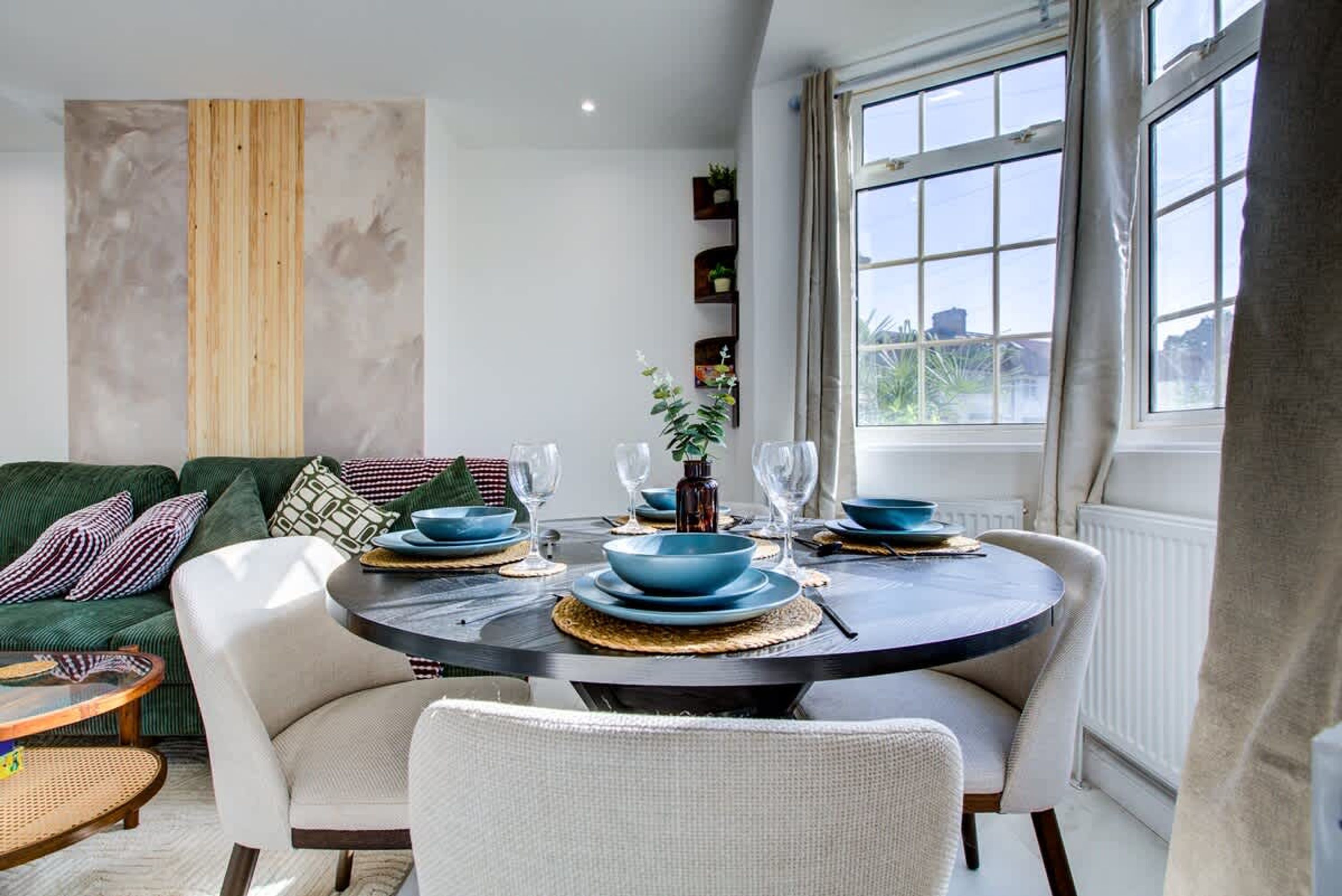 Un coin repas avec une table ronde, des chaises et de la vaisselle bleue.