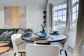A dining area with a round table, chairs, and blue tableware. - Perfect Booking Stylish 3 Bed House in Enfield (Enfield)